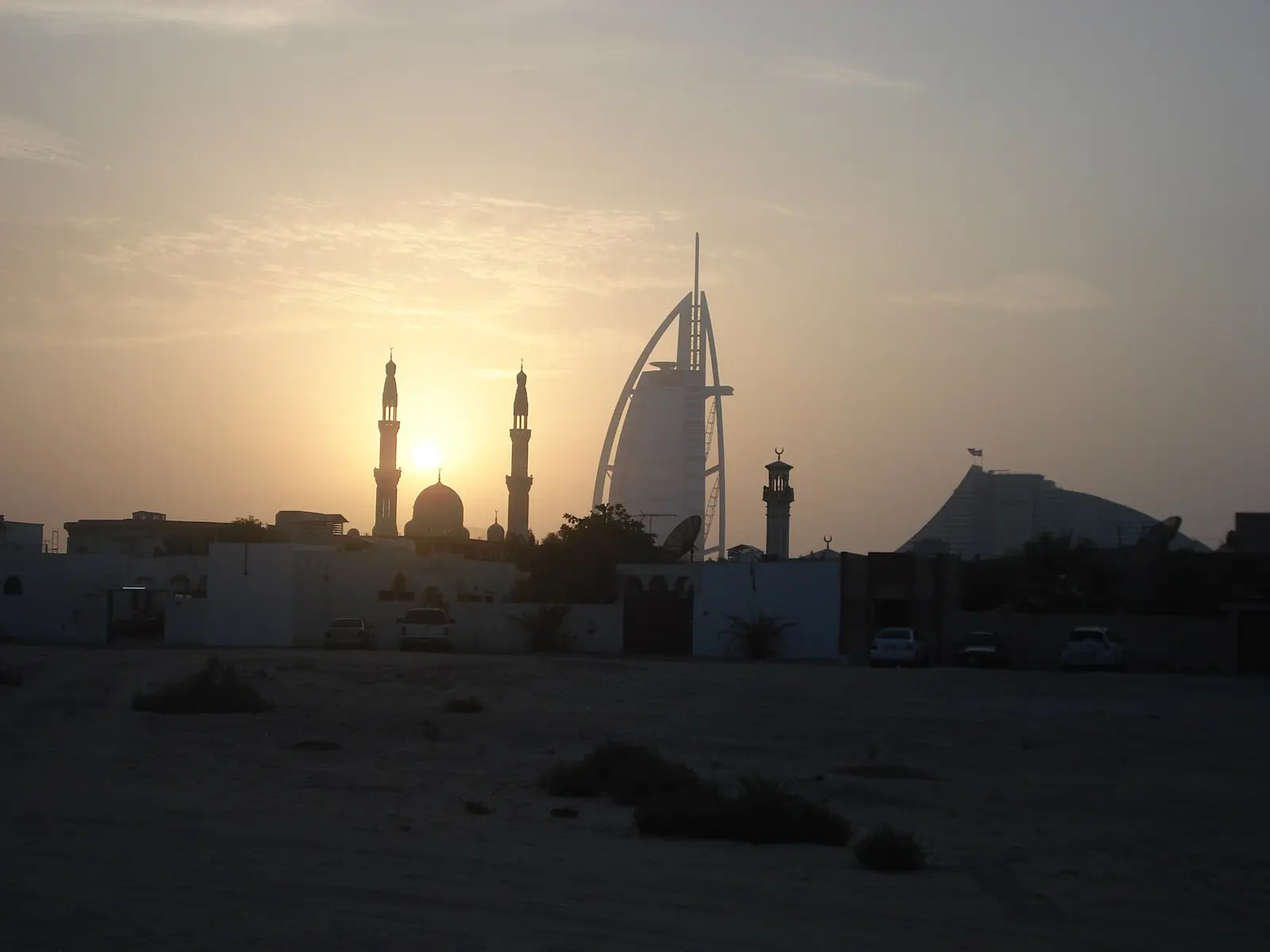 Burj Al Arab and a mosque silhouetted at sunset, Dubai